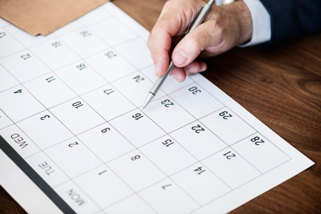 Homem segurando uma caneta em um calendário. Imagem inserida no texto: o que os melhores escritórios de advocacia tem a ensinar.